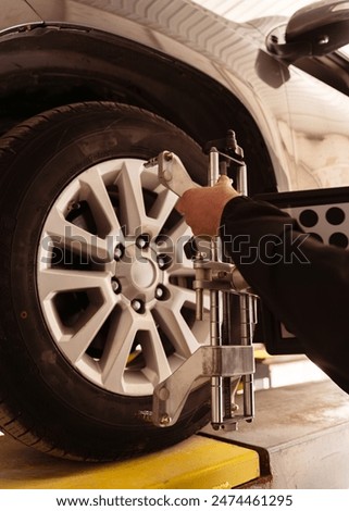 Auto mechanic installing sensor during suspension adjustment and automobile wheel alignment work at repair service station. Close up