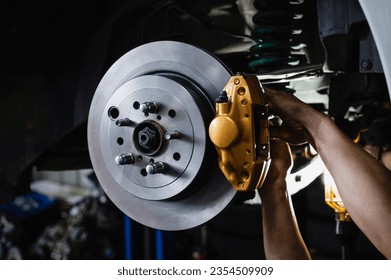 Auto mechanic installing two piston brake calipers and disc brake rotors ,car rear brake repair and service.  - Powered by Shutterstock