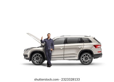 Auto mechanic leaning on a SUV with an open hood and gesturing thumbs up isolated on white background  - Shutterstock ID 2323328133