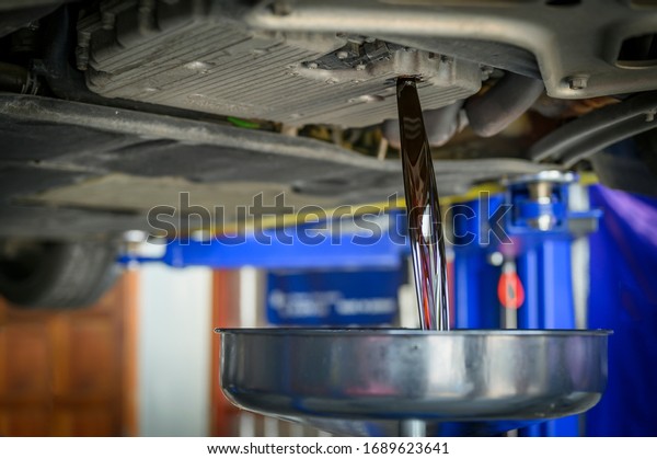 Auto mechanic loosen\
auto transmission oil drain plug. Then let the old used oil flow\
out of the oil pan.