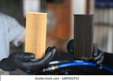 Auto Mechanic Makes A New Oil Filter Change. By Holding An Old Oil Filter Compared To A New One.