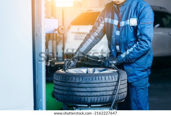 Auto mechanic making car tire\
pressure check on the removed wheel in the auto service\
garage