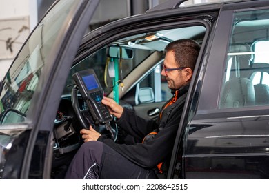 Auto Mechanic Man In A Car. Car Electrician Checks The Car