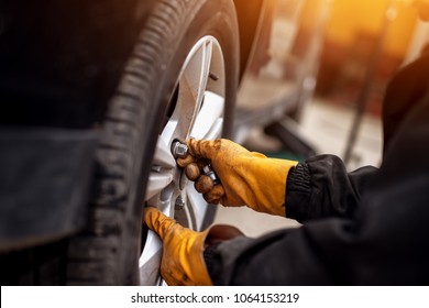 Auto mechanic man with electric screwdriver changing tire outside. Car service. Hands replace tires on wheels. Tire installation concept.