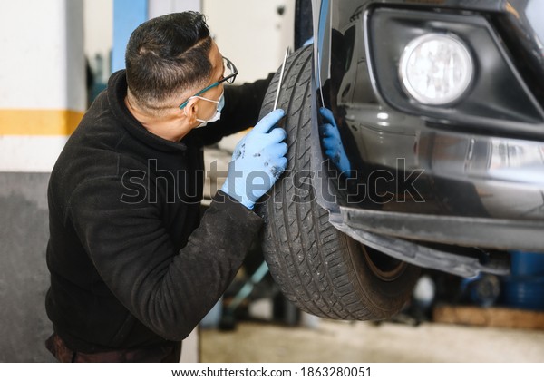 Auto mechanic man with face mask working at\
auto repair shop. High quality\
photo
