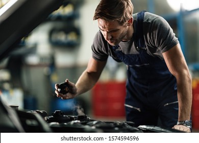 Auto Mechanic Opening Radiator Cap And Checking Overheated Car Cooling System In A Workshop. 