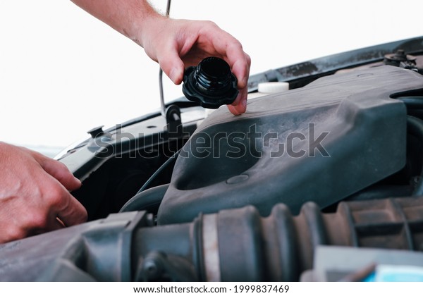 An\
auto mechanic opens the oil filler plug to change the oil. Auto\
mechanic working on car engine in mechanics\
garage.