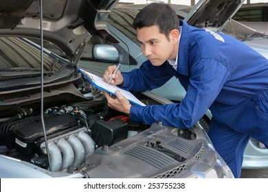 Auto mechanic (or technician) checking car engine at the garage