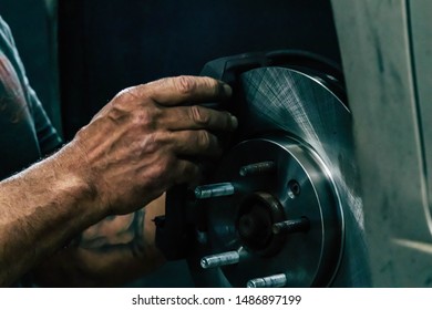 Auto Mechanic Performing A Brake Job And Maintenance Repair On A Car Being Serviced. Replacing Brake Rotor, Pads And Caliper.