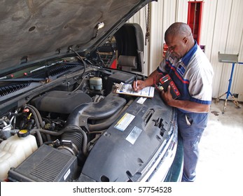 Auto mechanic performing a routine service inspection in a service garage.