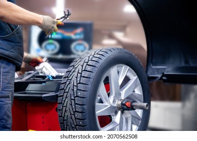 Auto mechanic places weights on steel rim of machine. Concept balancing wheel in car service.