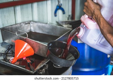 Auto mechanic pouring old used automatic transmission fluid into the oil drum tank.