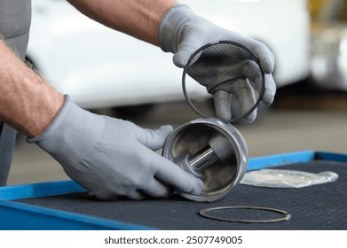 An auto mechanic prepares the installation of pistons during engine repairs. Close-up. An auto mechanic checks the cleanliness, serviceability, and integrity of the piston ring grooves. - Powered by Shutterstock