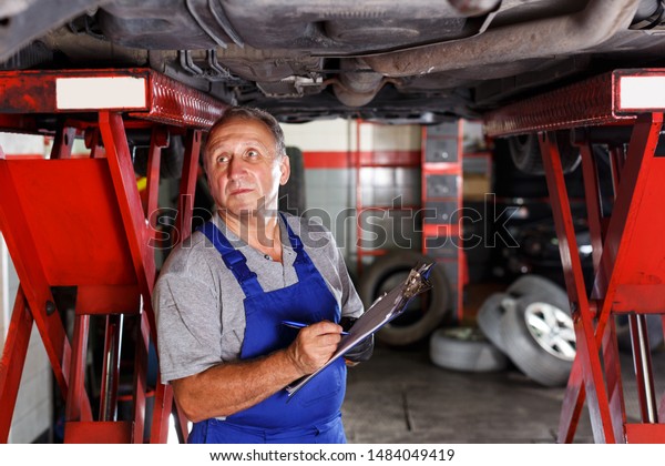  auto mechanic recording list of works on car\
repair in auto workshop
