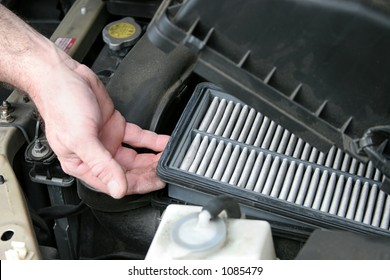 An auto mechanic removing the dirty air filter from an automobile.