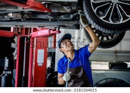 Auto mechanic repairman using a socket wrench working auto suspension repair in the garage, change spare part, check the mileage of the car, checking and maintenance service concept.