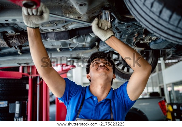 Auto
mechanic repairman using a socket wrench working auto suspension
repair in the garage, change spare part, check the mileage of the
car, checking and maintenance service
concept.