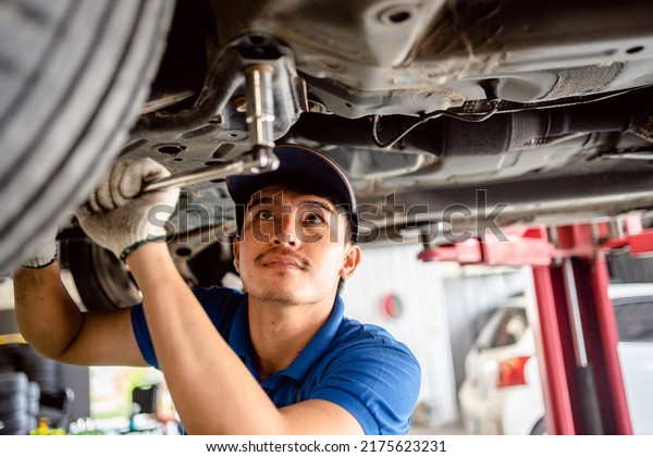 Auto\
mechanic repairman using a socket wrench working auto suspension\
repair in the garage, change spare part, check the mileage of the\
car, checking and maintenance service\
concept.