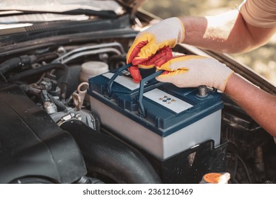 auto mechanic repairs a car. A mechanic removes a car battery from the box.