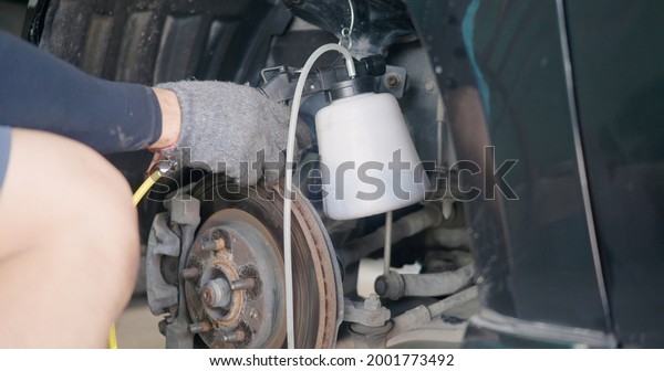 Auto mechanic replacing brake fluid on a vehicle,\
technician bleed air out of disc brake system in garage workshop,\
Car repair in a car\
service