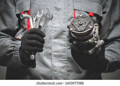 Auto mechanic showing a broken air conditioning compressor close up. - Shutterstock ID 1693977088