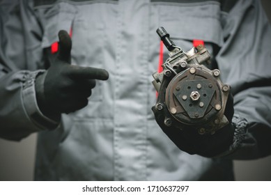 Auto Mechanic Showing A Broken Air Conditioning Compressor Close Up.