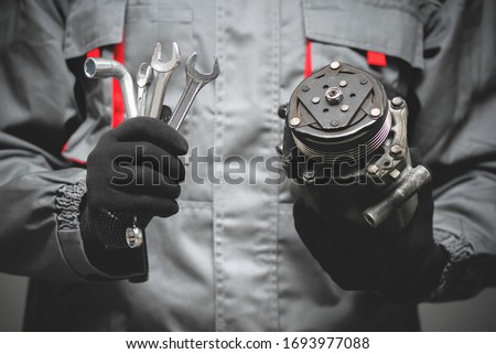 Auto mechanic showing a broken air conditioning compressor close up.