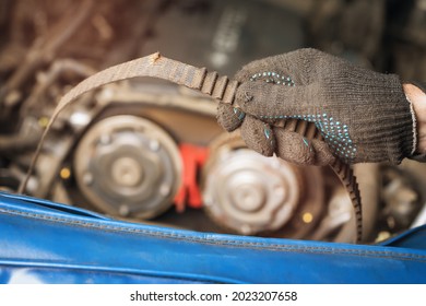 Auto mechanic shows a torn timing belt and peeled teeth on it, close-up