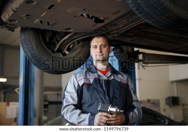 Auto mechanic smiling in\
his garage