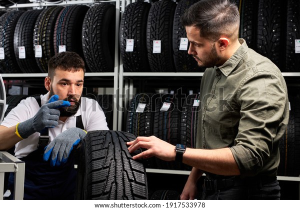auto mechanic talk about\
advantages of auto tire to young client in service, man came to buy\
new tire for his automobile, stand talking and examining the\
product