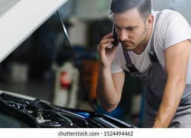 Auto mechanic talking on mobile phone in auto repair shop - Powered by Shutterstock