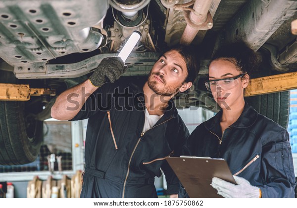 Auto mechanic team\
working help support together to checking under car for service\
maintenance in garage