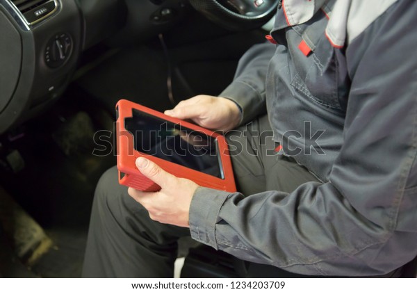 Auto\
mechanic testing the electrical system on\
automobile