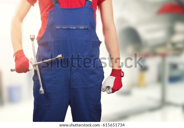 auto\
mechanic with tire wrench in hand in car\
service