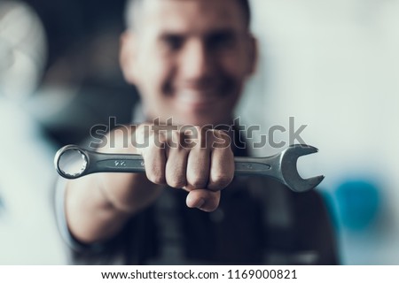Auto Mechanic with Tool on Blurred Background. Close-up of Repairman Strong Fist Holding Metalic Wrench in Garage. Automobile Repair Service Concept. Automobile Master Concept