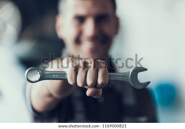 Auto Mechanic\
with Tool on Blurred Background. Close-up of Repairman Strong Fist\
Holding Metalic Wrench in Garage. Automobile Repair Service\
Concept. Automobile Master\
Concept