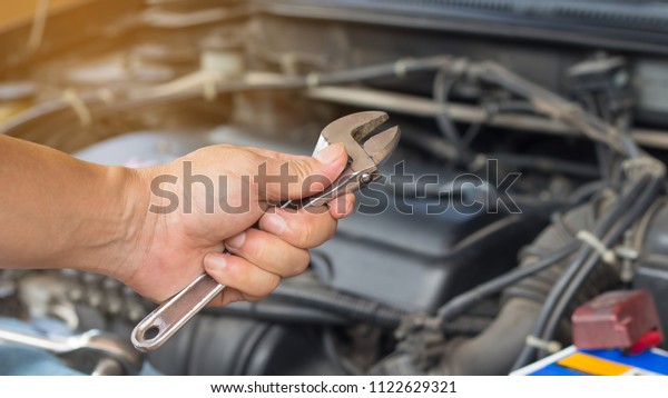 Auto\
mechanic with tool working check and fixed an old car engine at\
service station,change and repair before\
drive\
