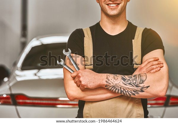 Auto mechanic with tools in car repair\
shop. Cropped photo. Close up view. Front\
view.