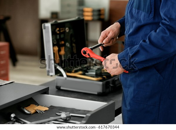 Auto mechanic with\
tools in car repair shop