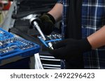 Auto mechanic with torque wrench at automobile repair shop, closeup