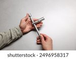 Auto mechanic with torque wrench at light grey textured table, closeup