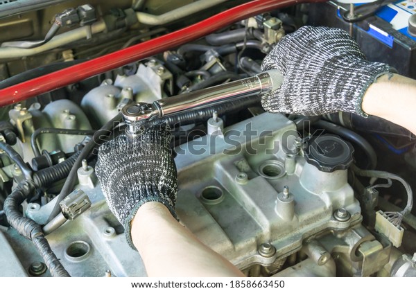Auto mechanic use torque wrench to adjust spark\
plug, Car maintenance\
service.