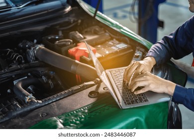 Auto mechanic uses laptop while conducting diagnostics test. Modifying the engine with a computer Check service. Auto service, repair, maintenance - Powered by Shutterstock