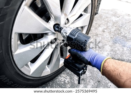 Auto mechanic using impact wrench cordless to change car wheel , Car repair concept