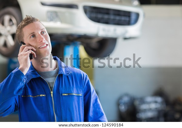Auto mechanic\
using mobile phone in\
workshop