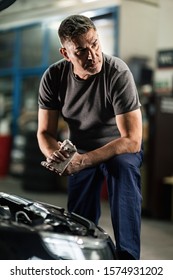 Auto Mechanic Using Rag And Wiping His Dirty Hands In Repair Workshop. 