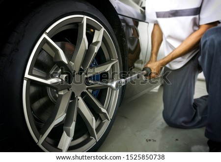 Auto mechanic using Torque wrench to inspection the wheel nuts for safety in travel in mechanics garage. Car repair center.