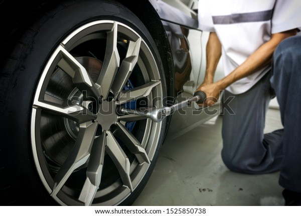 Auto mechanic using Torque wrench to inspection\
the wheel nuts for safety in travel in mechanics garage. Car repair\
center.