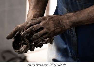 An auto mechanic wipes his dirty hands after repairing a car, close-up. Man's hands in machine motor oil. - Powered by Shutterstock