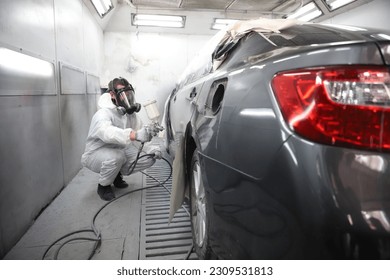 auto mechanic worker painting, automobile repairman painter in protective workwear and respirator painting car body in paint chamber - Powered by Shutterstock